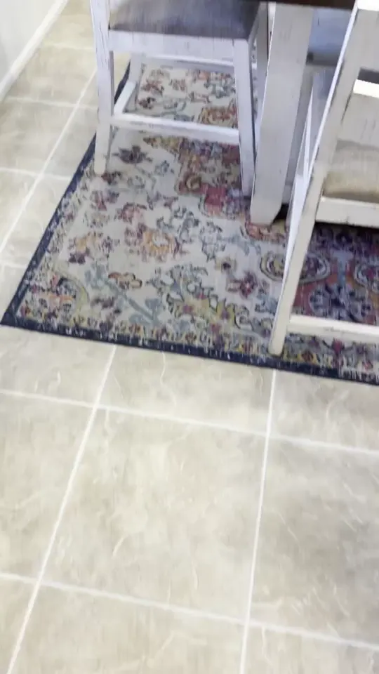 Light ceramic tile floor with even white grout near a dining table, from a similar job