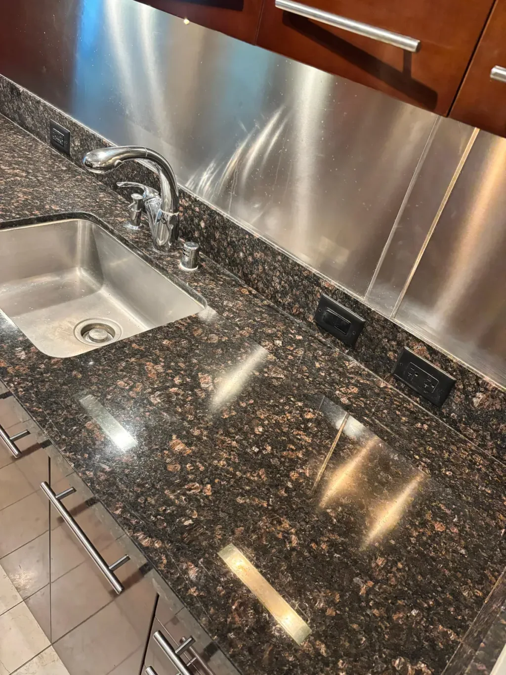 The same dark granite countertop and sink after the crack was filled and polished