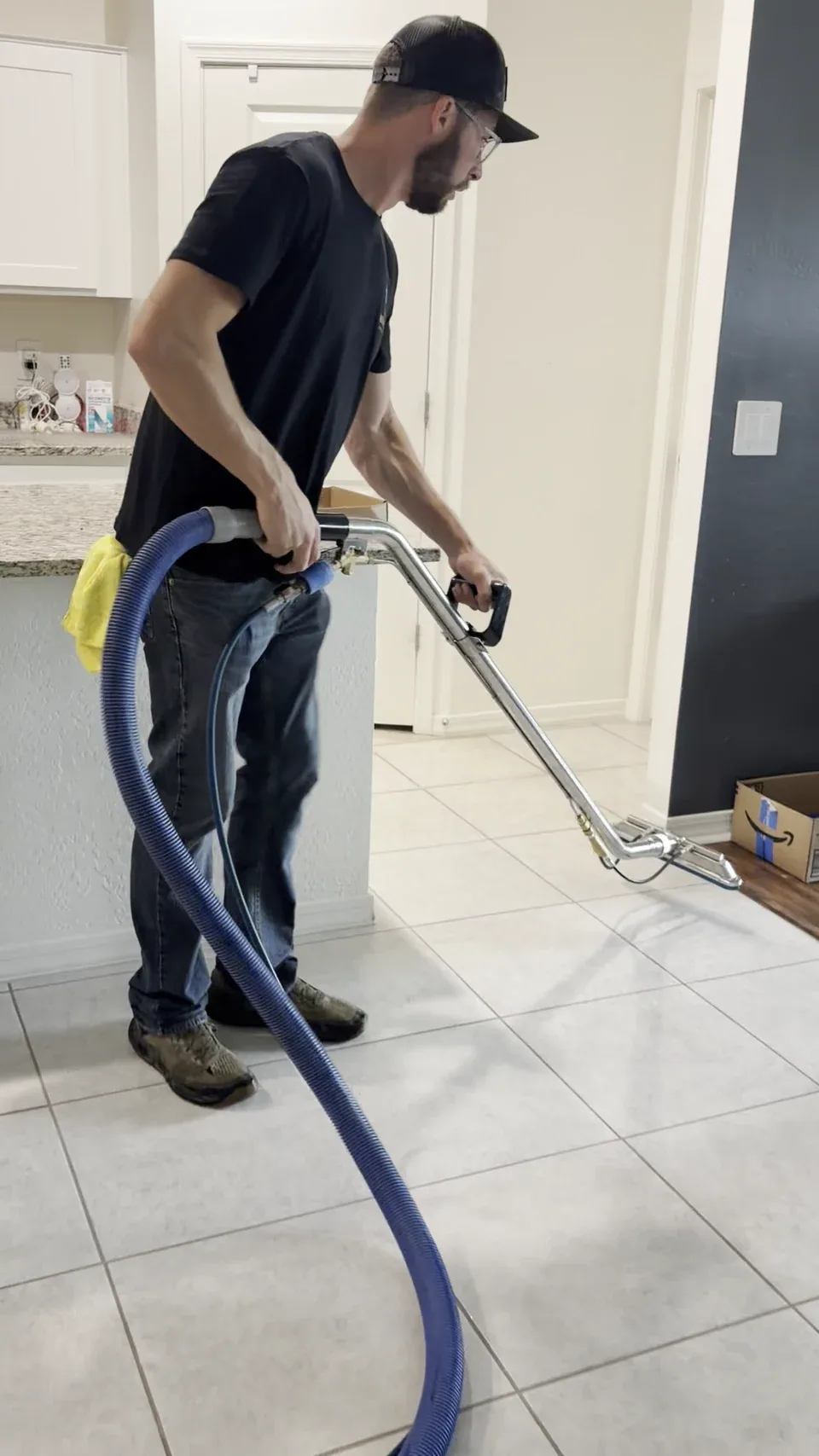 Justin Brevik cleaning a light-colored tile floor with an extraction wand