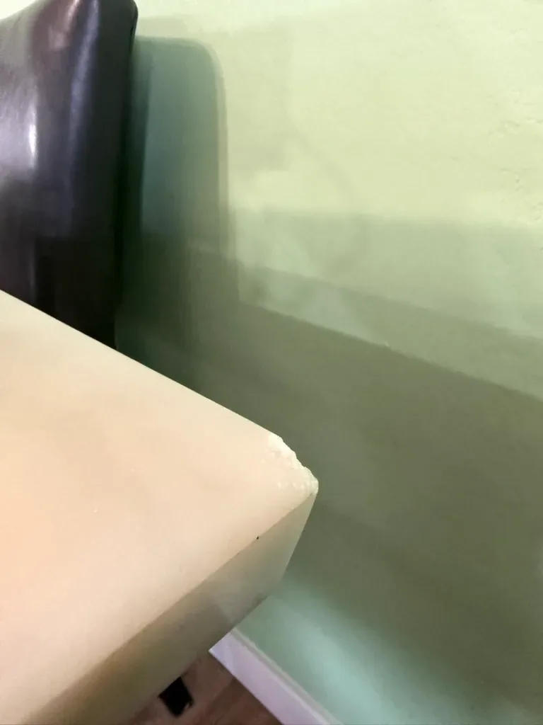 Corner of a pale marble table with a chip broken out of the top edge