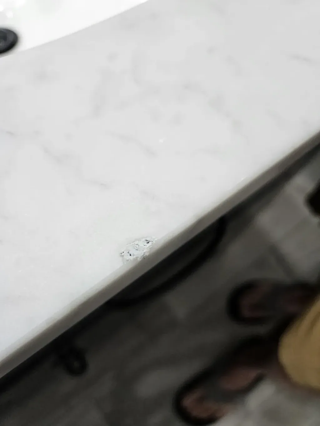 Small chip in the front edge of a white veined marble bathroom vanity