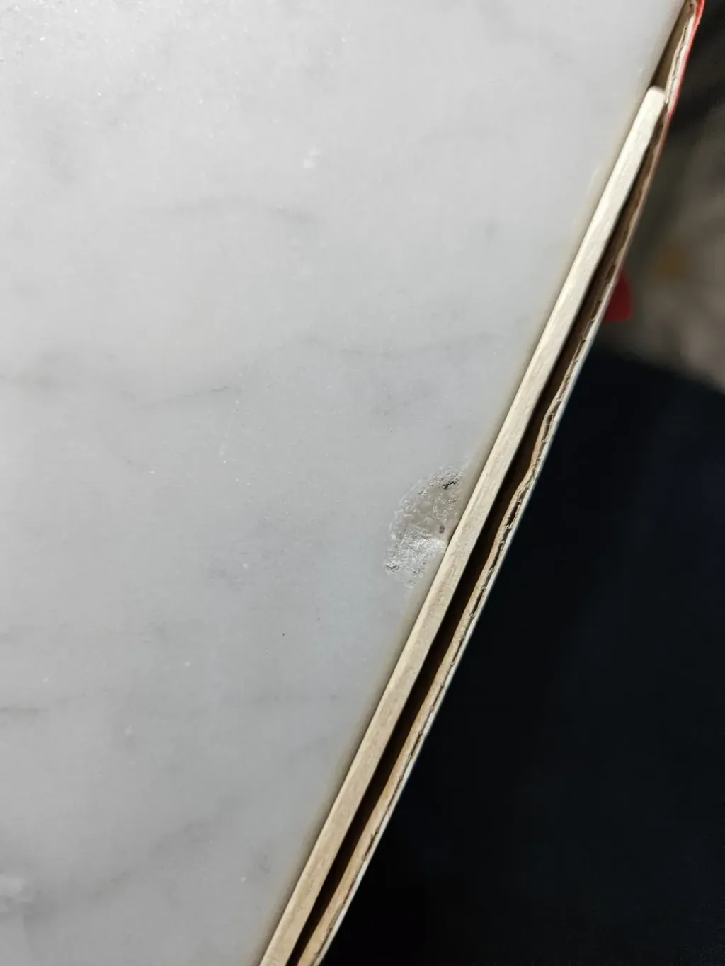 Close view of a chip broken out of the edge of a white marble vanity