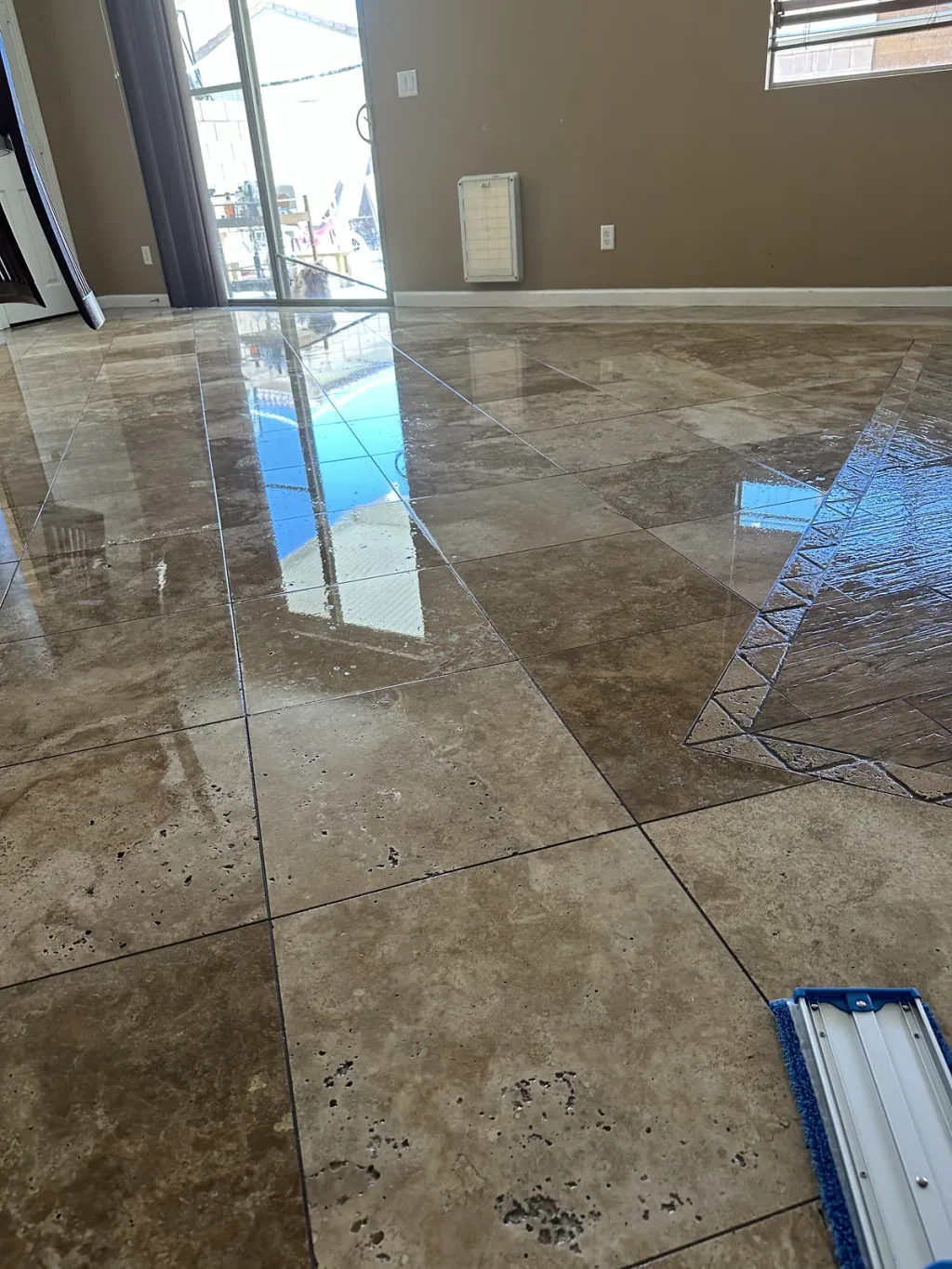 Natural travertine floor in an Ocotillo home with a wet reflective finish after restoration work