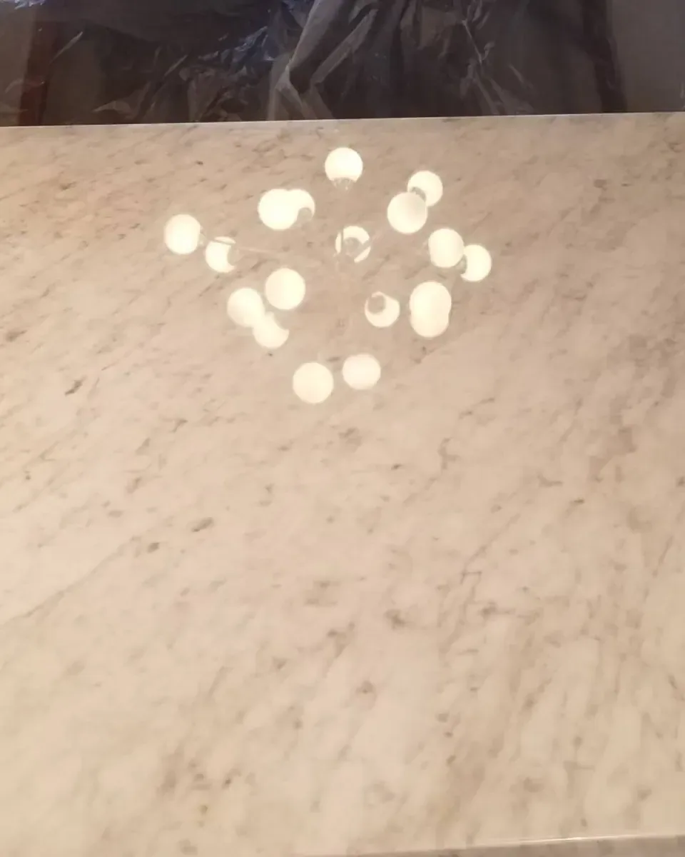 Polished white marble countertop reflecting a chandelier evenly across its surface