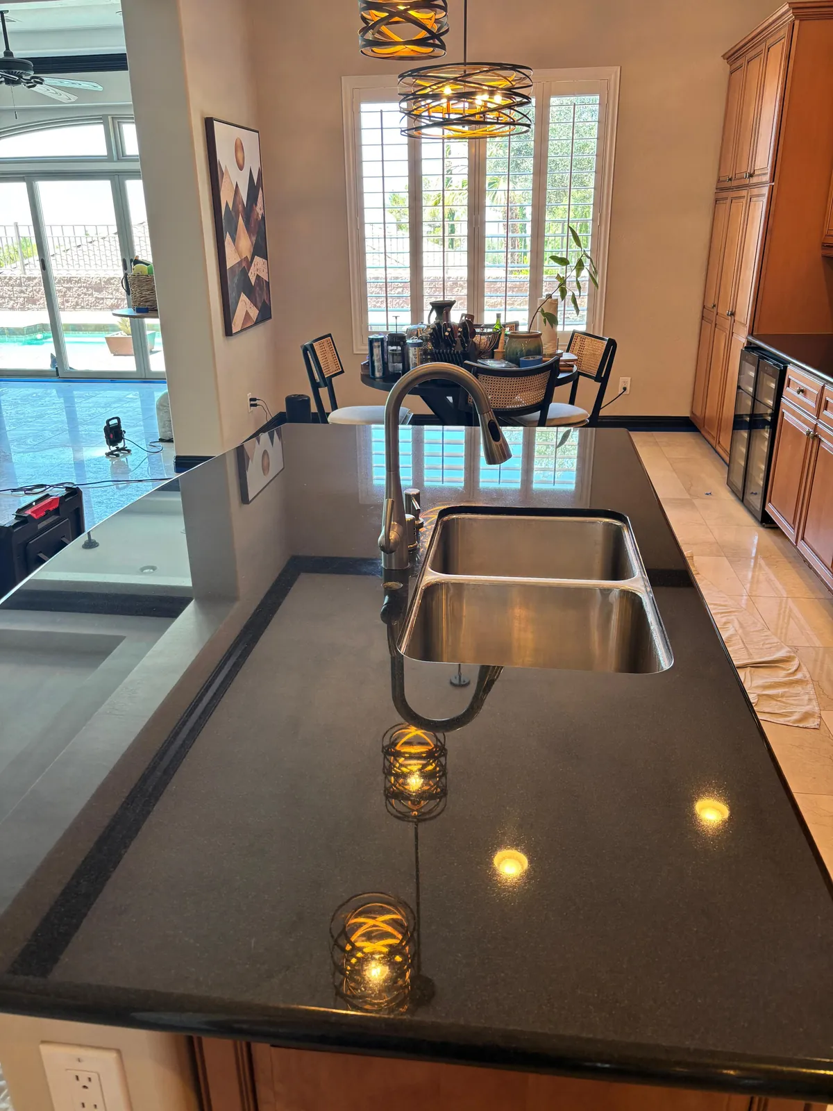 Dark granite kitchen countertop with a clear polished reflection around the sink