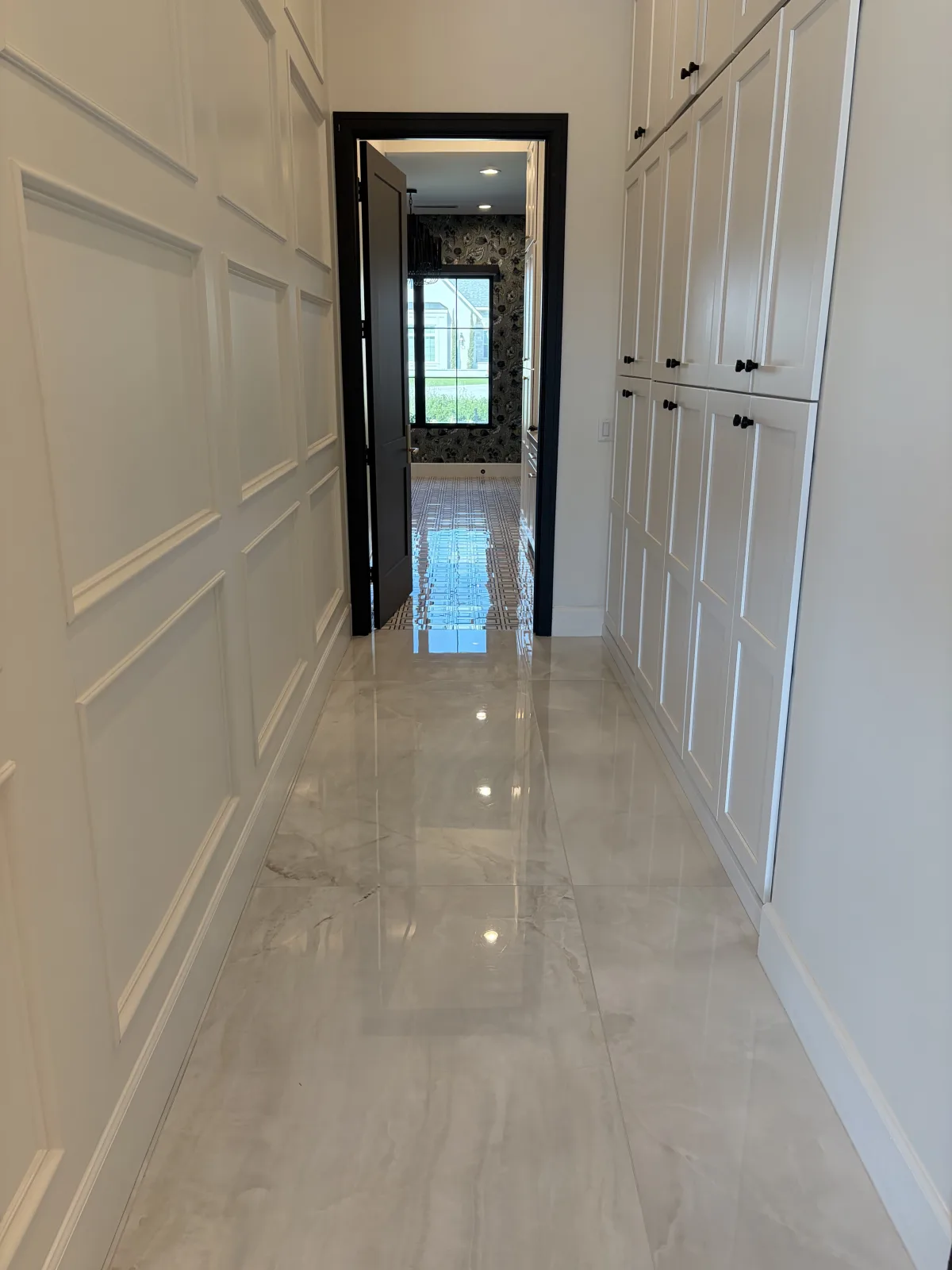 Polished marble floor carrying reflection through a finished residential hallway