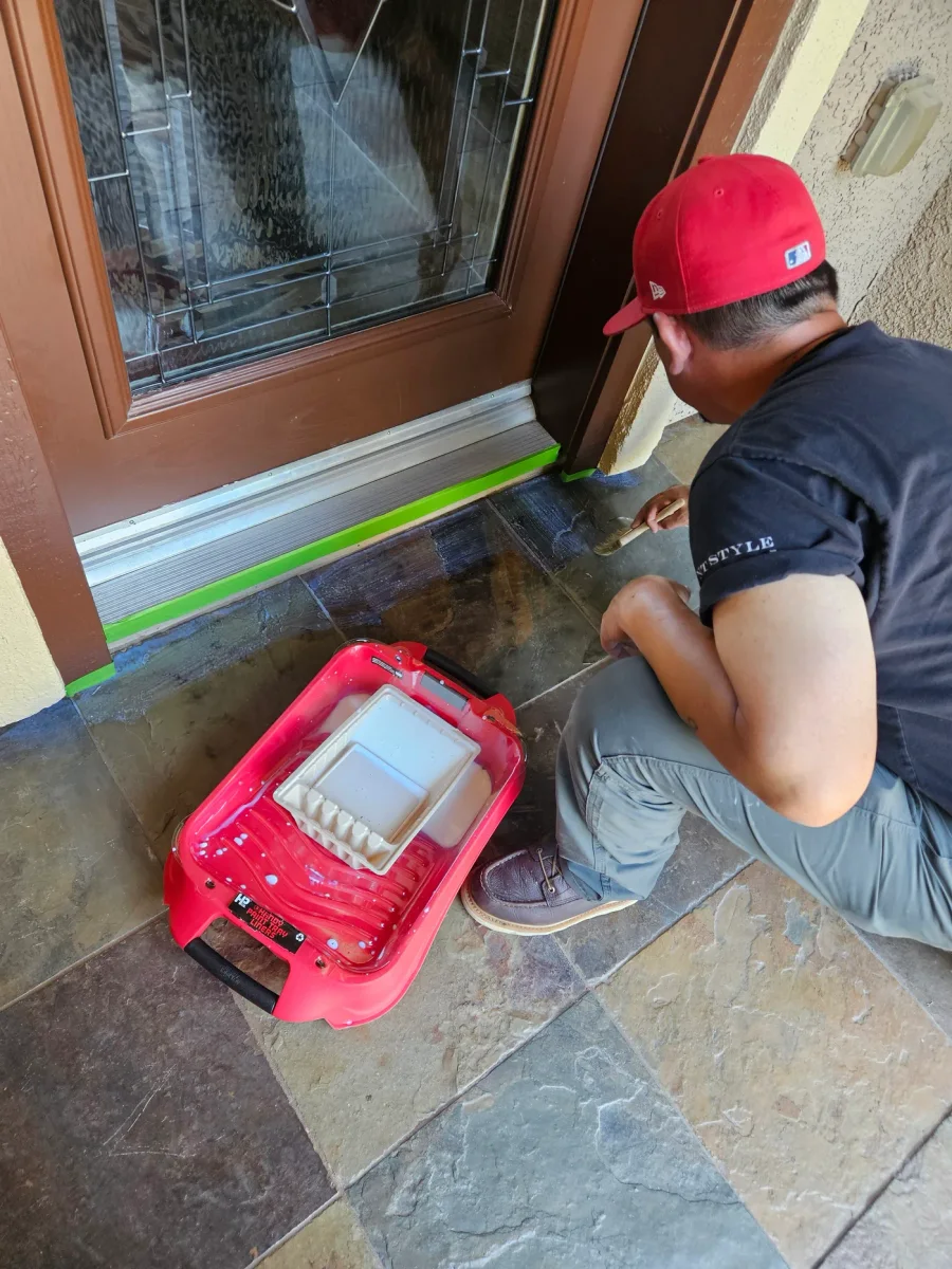 Technician masking a door threshold with tape before sealing the stone paving up to the edge