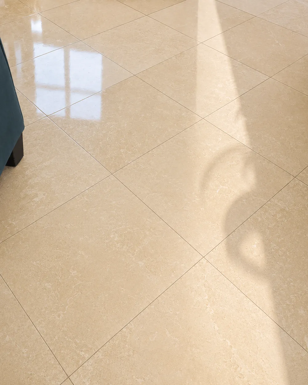 Stone tile floor polished to an even sheen, the window and its frame reflected across several tiles