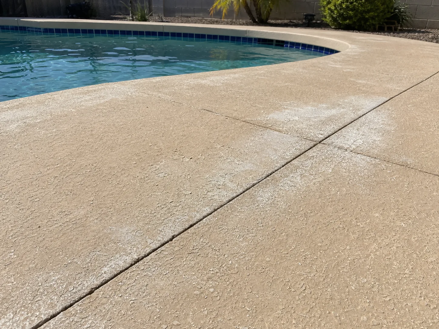 Cloudy white patches where pool deck sealer has begun to fail