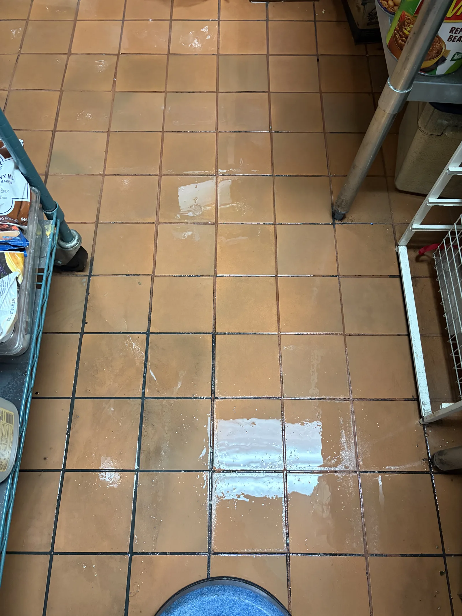 Commercial tile floor with cleaning solution and equipment at the edge of the work area