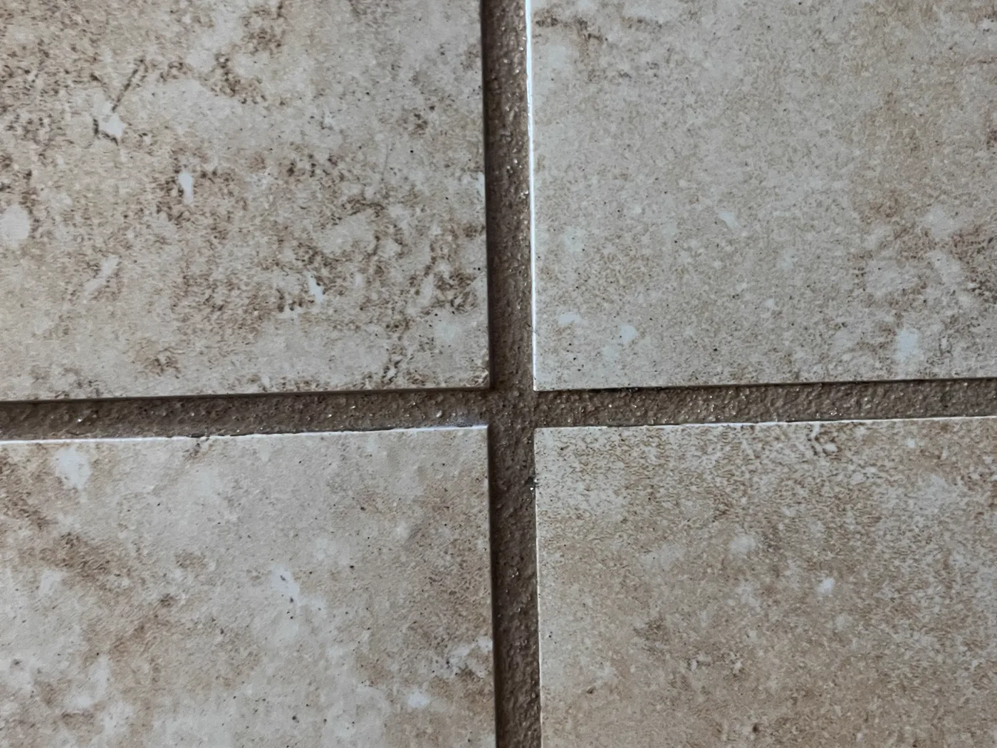 Close view of travertine floor tile and the grout joints between them under raking light
