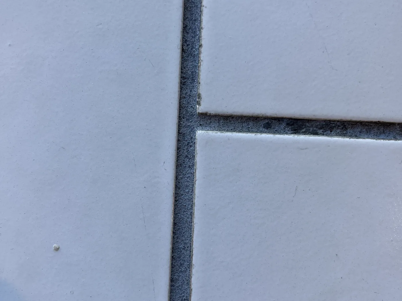 Close view of the joint where two tiled planes meet, showing where flexible sealant belongs instead of rigid grout