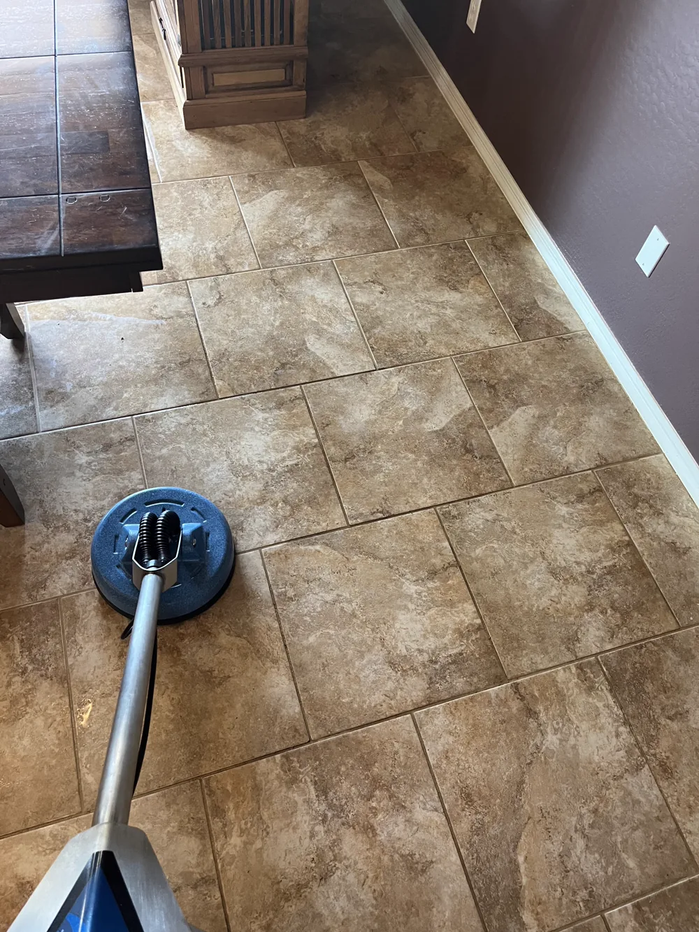 Technician working an extraction tool across a travertine tile floor in a Phoenix-area home