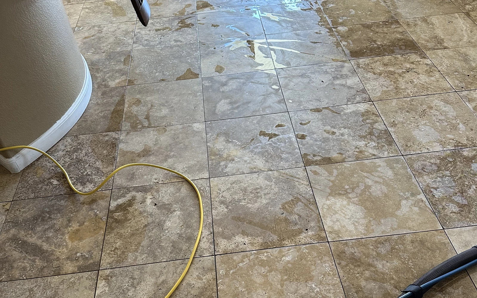 Natural travertine floor with open voids and restoration hoses during wet cleaning
