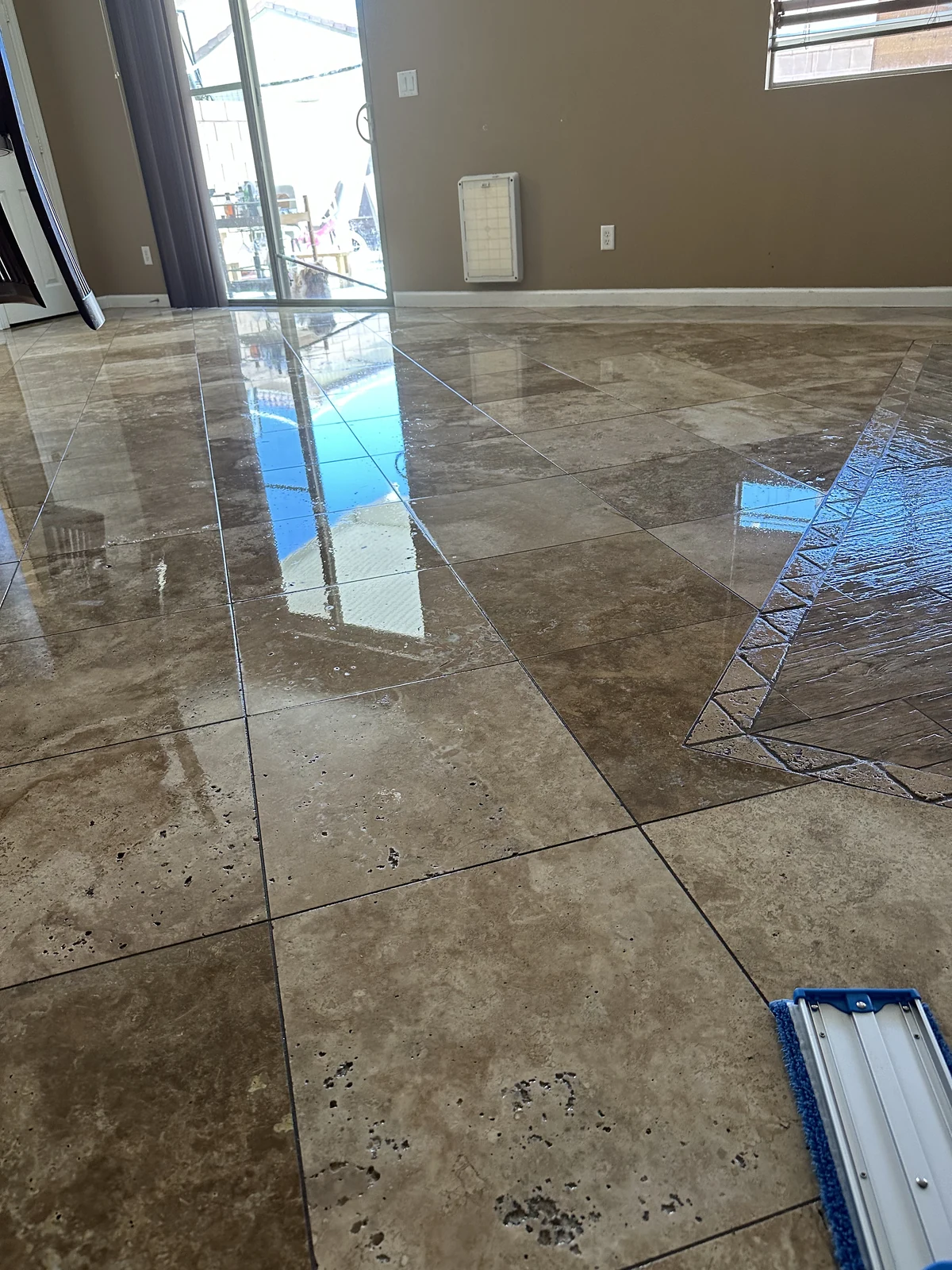 Restored natural travertine floor reflecting light across a residential room in Ocotillo