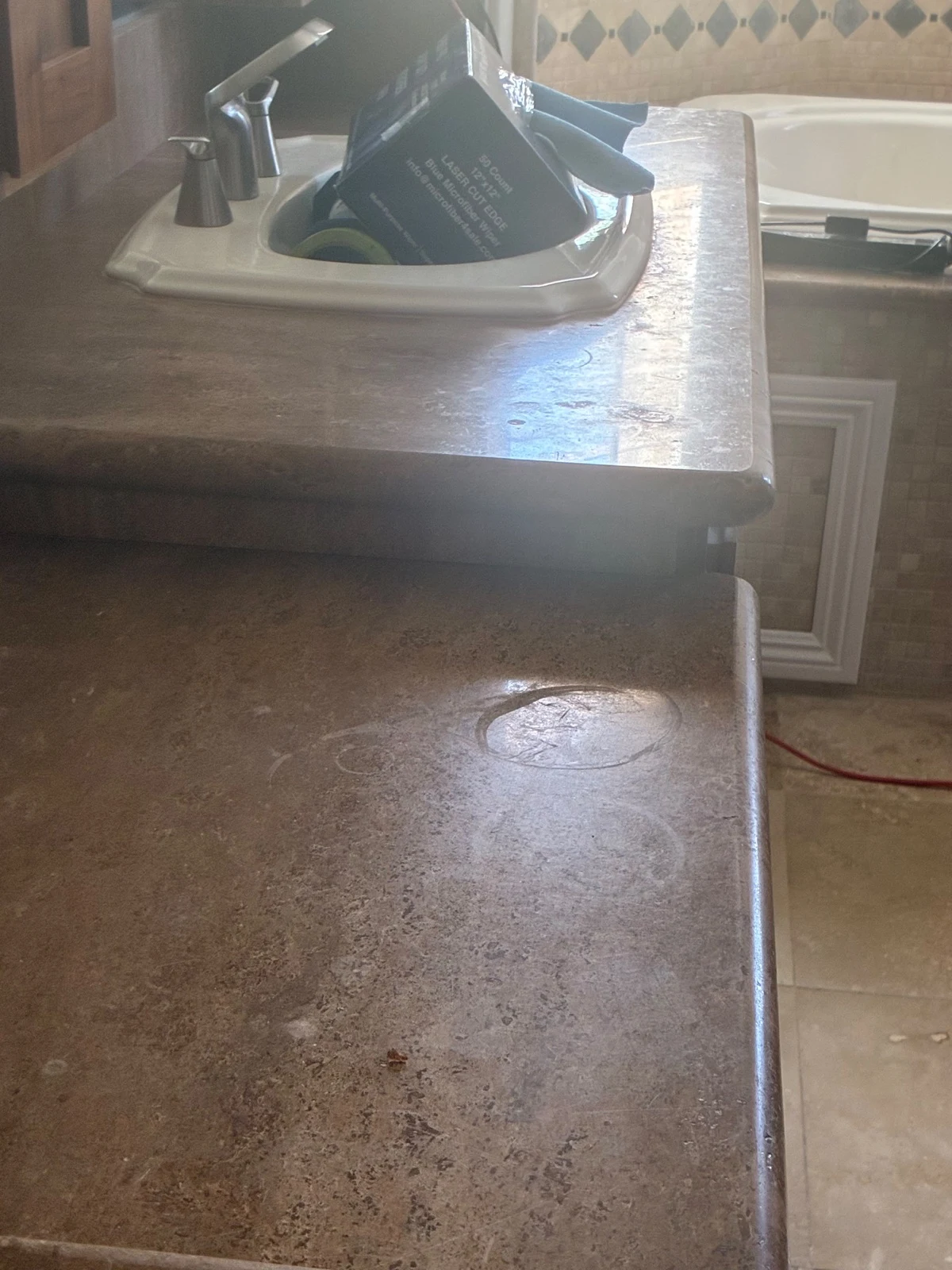 Stone vanity countertop with a dull, etched surface and visible water rings before restoration